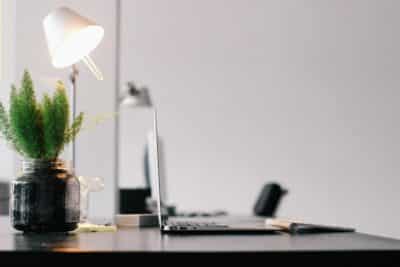 Stylish modern office desk with laptop, lamp, and indoor plant for productive work environment.