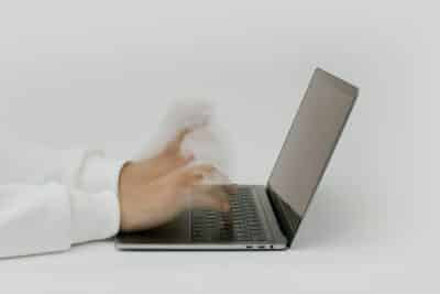Hands rapidly typing on a laptop, illustrating speed and technology in a digital work environment.