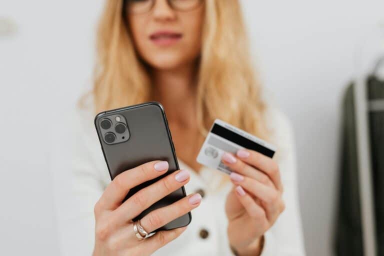 Close-up of a woman using a smartphone and credit card for online shopping.